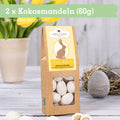 Osterbundle mit 2x Kokosmandeln (60g) in weißer Schokolade. Festliche Verpackung mit Osterhasenmotiv, ideal für genussvolle Ostertage.