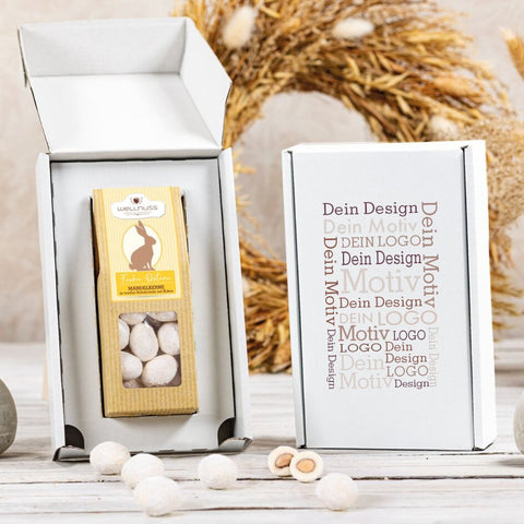 Geschenkkarton mit 1 Ostersnack, individuell gestaltbar mit eigenem Design. Enthält Mandelkerne in weißer Schokolade mit Kokosraspeln.