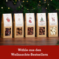 Auswahl an Weihnachts-Snacks in stilvollen Verpackungen mit verschiedenen Nussvarianten. Perfekt als festliches Geschenk oder Genussmoment.