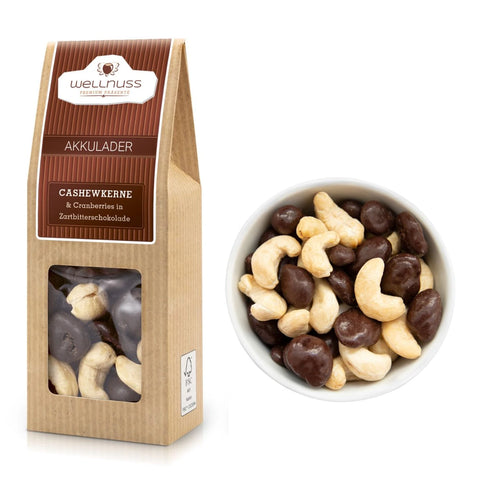 Akkulader - Cranberries in Zartbitterschokolade & Cashewkerne (70 g) in umweltfreundlicher Verpackung mit Sichtfenster, daneben eine Schale mit der Mischung.