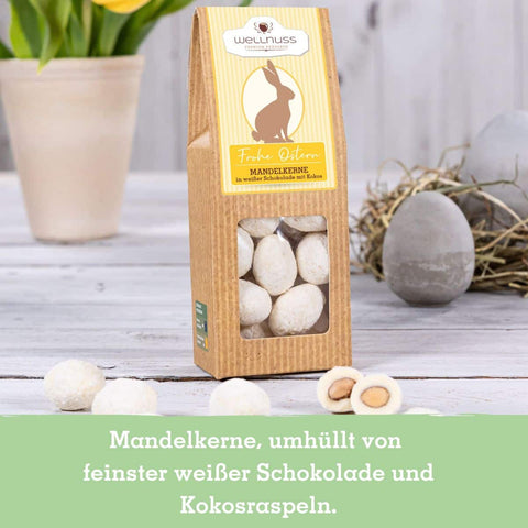 Mandelkerne umhüllt mit weißer Schokolade und Kokosraspeln, edle Ostersnacks in stilvoller Verpackung mit Osterhasen-Motiv.